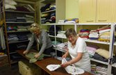 Foto: Eine Seniorin zwischen den Regalreihen in einer Kleiderkammer.